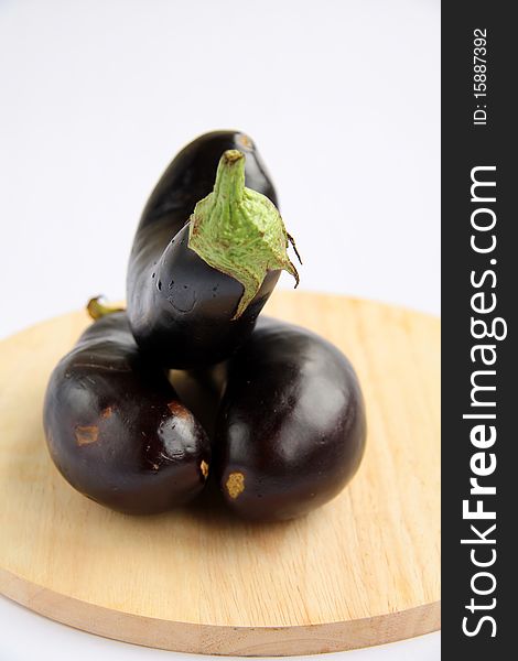 Three eggplants on a wooden board on a white background