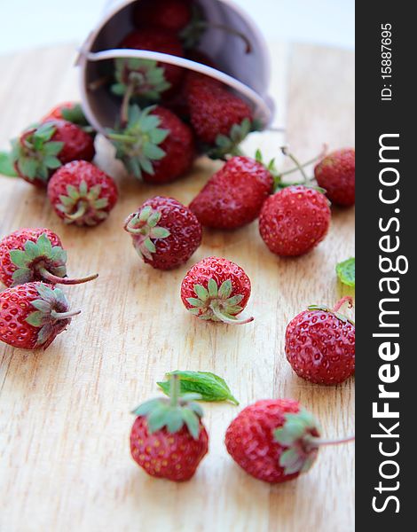 Pink bucket with a strawberry on a wooden board