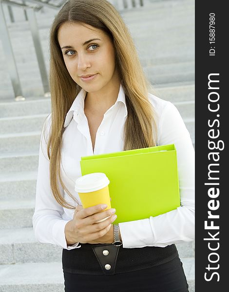 Business woman with a green folder and paper cup of coffee. Business woman with a green folder and paper cup of coffee