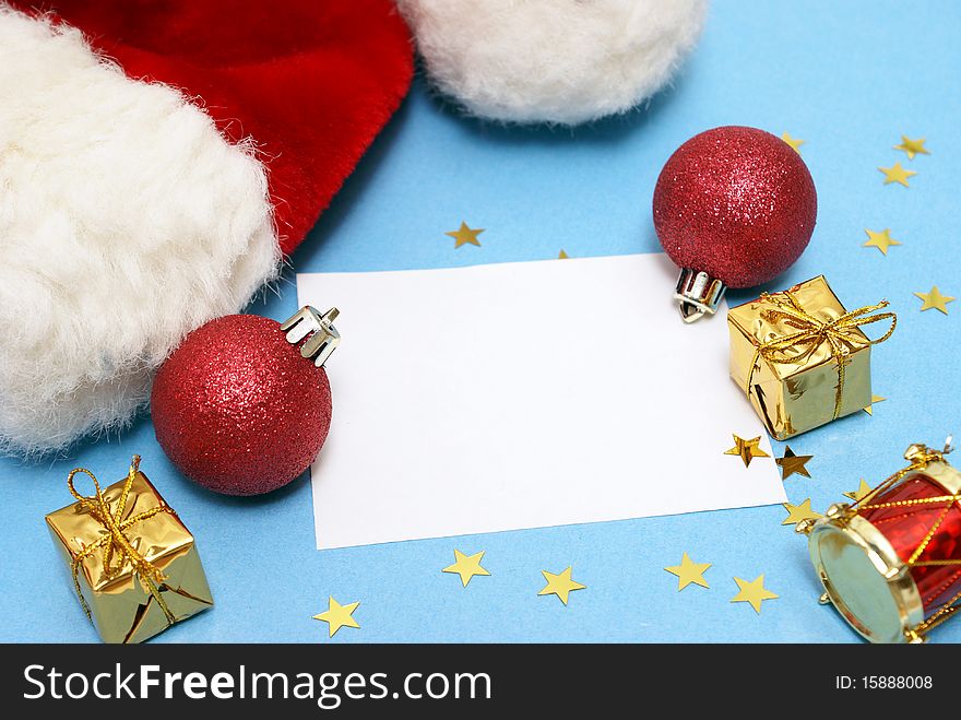 A blank Christmas note with various decorations and a Santa hat.