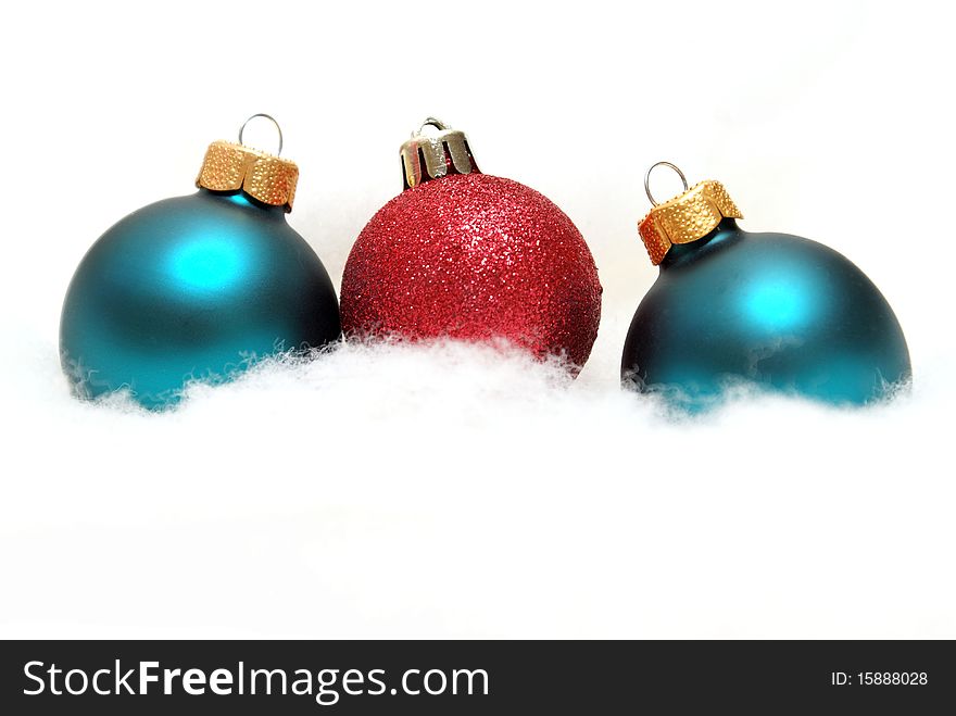 Three holiday baubles on some fake snow.