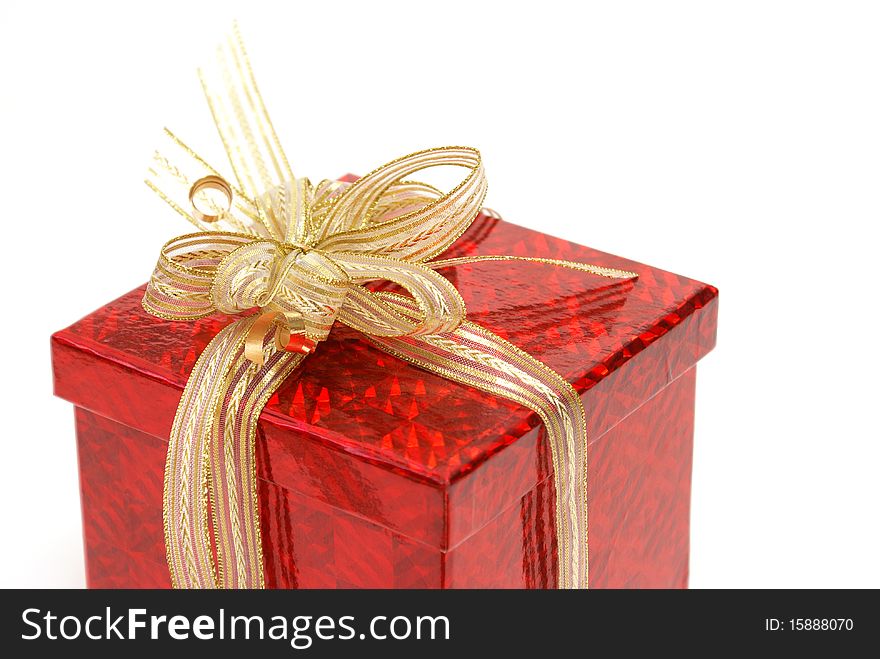 A macro shot of a red gift box with some golden ribbon wrapped around it.