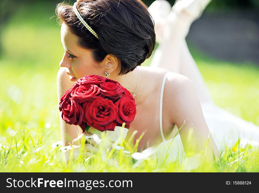 Bride in white dress lying down in  grass.