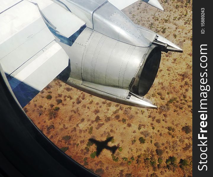 A plane and its shadow flying over a landscape. A plane and its shadow flying over a landscape