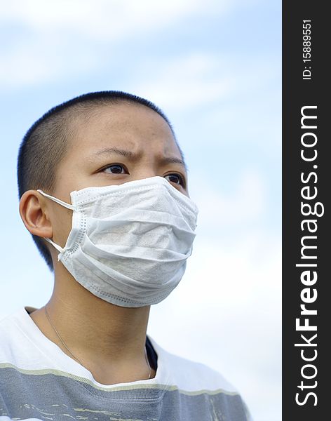 Sad masked female teen outdoors wearing striped shirt with shaved head. Sad masked female teen outdoors wearing striped shirt with shaved head