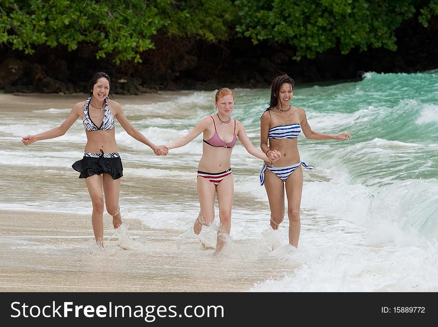 Three girls run on the beach, teenager on vacation at the sea