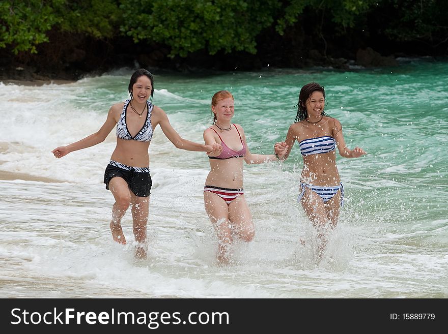 Three girls run on the beach