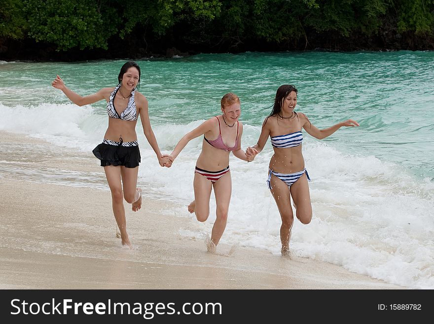 Three girls run on the beach, teenager on vacation at the sea