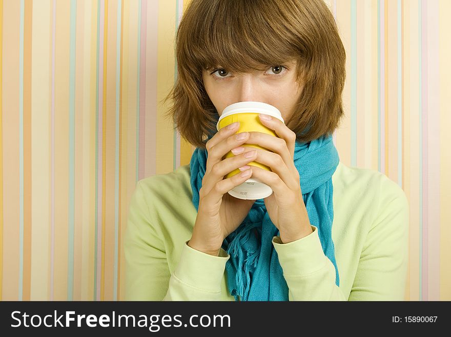Young girl in a room drinking coffee / tea from a paper cup. Young girl in a room drinking coffee / tea from a paper cup
