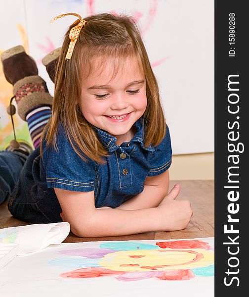 Smiling little girl looking at her art work. Smiling little girl looking at her art work