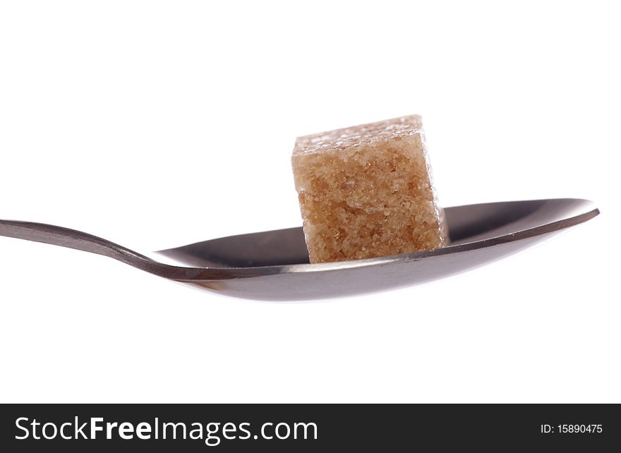 One brown sugar cube on a tea spoon cutout. One brown sugar cube on a tea spoon cutout