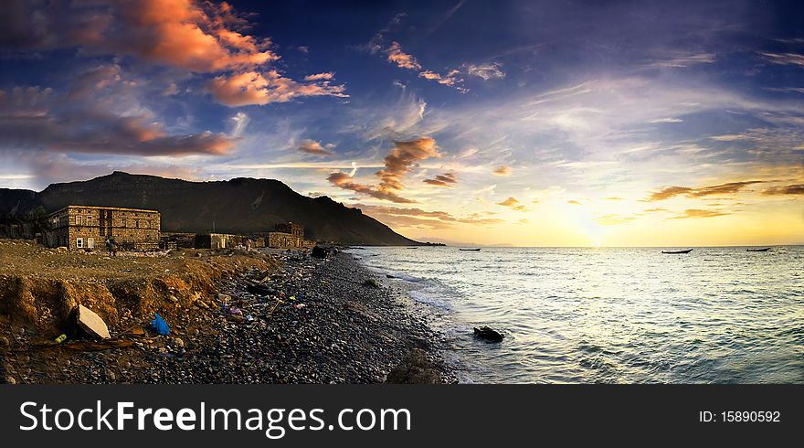 Picturesque sunset and cloudscape over rocky coastline with silhouetted boat in background, Socotra or Soqotra island in Indian ocean. Coast arount the main city of Socotra called Hadibo. Picturesque sunset and cloudscape over rocky coastline with silhouetted boat in background, Socotra or Soqotra island in Indian ocean. Coast arount the main city of Socotra called Hadibo