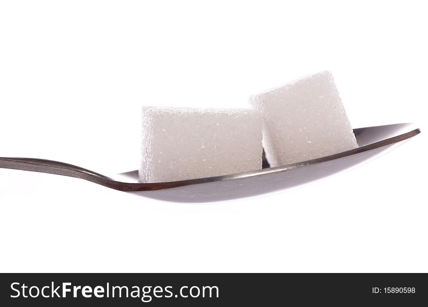 Two white sugar cubes on tea spoon
