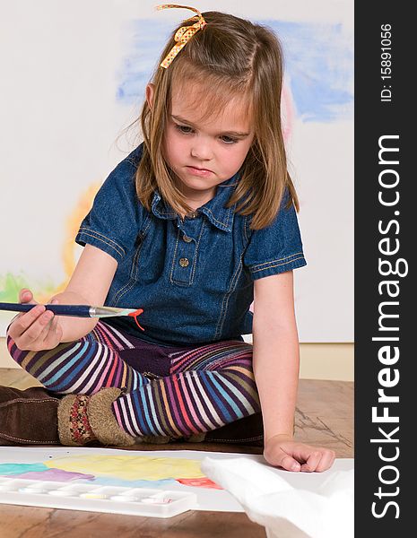 Little girl watching as paint drips from her paintbrush. Little girl watching as paint drips from her paintbrush