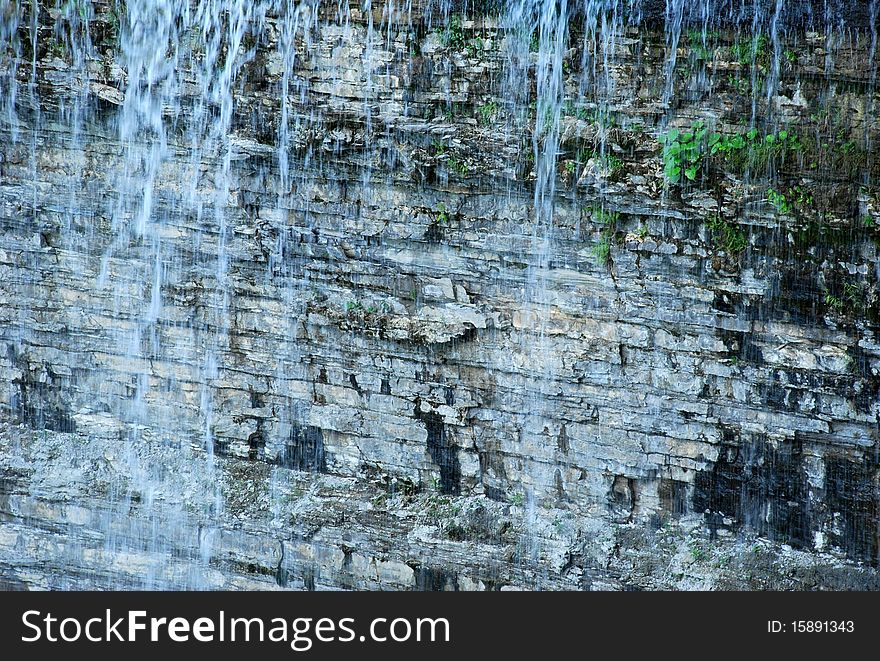 Waterfall on the background with stone wall