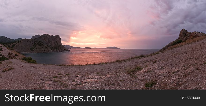 Purple sunrise on rocky bay