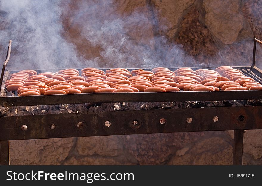 Sausages cooking on the grill in the background . Sausages cooking on the grill in the background .