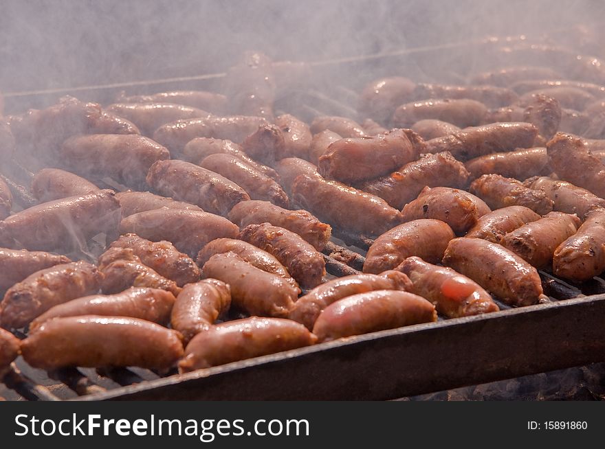 Sausages cooking on the grill in the background . Sausages cooking on the grill in the background .