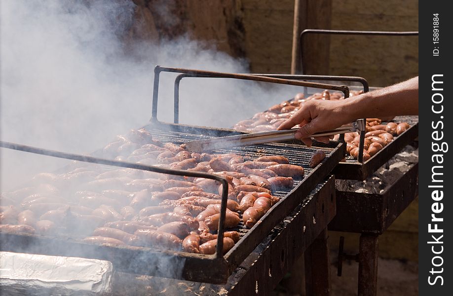 Sausages cooking on the grill in the background . Sausages cooking on the grill in the background .