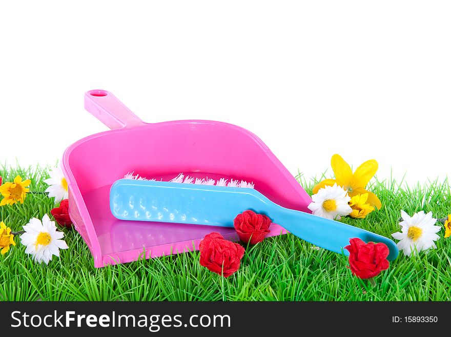 A dustpan and a brush on a flowery green lawn isolated over white