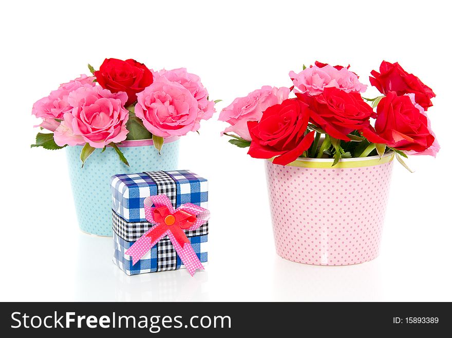 Red and pink roses in a dotted vases and a colorful present isolated over white. Red and pink roses in a dotted vases and a colorful present isolated over white