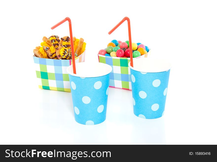 Checkered colorful cups with cookies and candy and drinking cups with straws isolated over white. Checkered colorful cups with cookies and candy and drinking cups with straws isolated over white