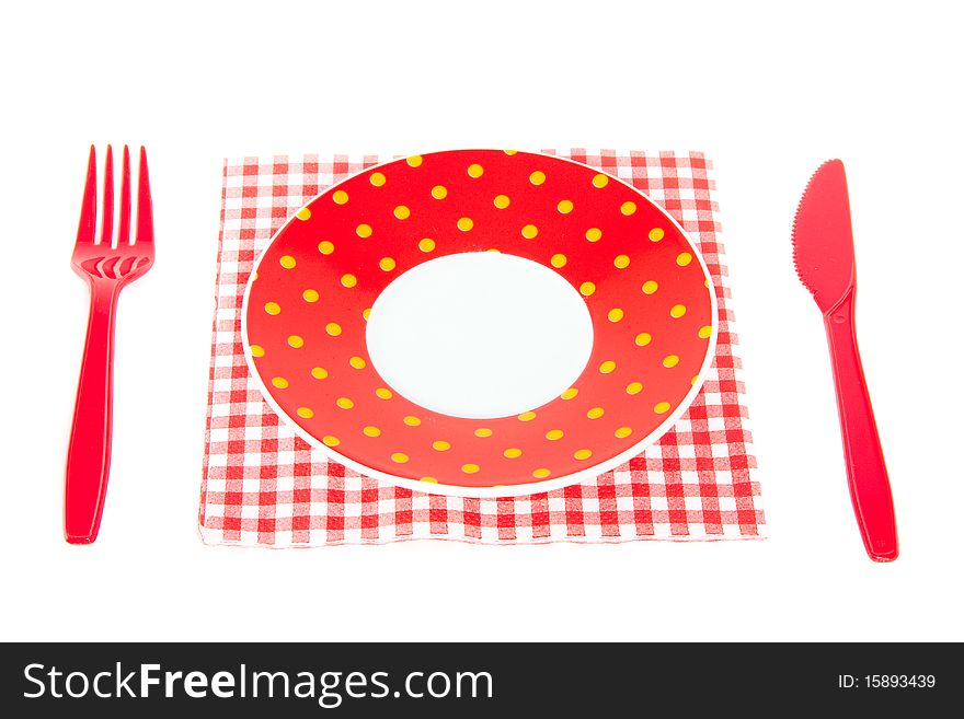 Plastic cutlery and a dotted saucer on a napkin isolated over white. Plastic cutlery and a dotted saucer on a napkin isolated over white