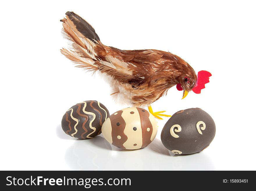 Three easter painted eggs in front of a chicken isolated over white