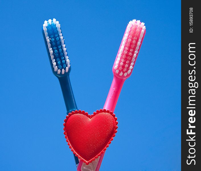 Two toothbrushes as a sign of love against a blue sky. Two toothbrushes as a sign of love against a blue sky