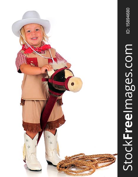 An adorable 2-year-old cowgirl riding her stick-horse by holding his ears. Isolated on white. An adorable 2-year-old cowgirl riding her stick-horse by holding his ears. Isolated on white.