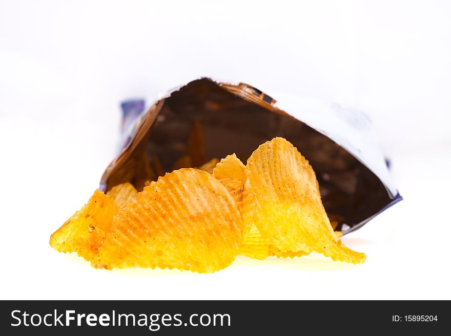 Spiced golden chips pile with the bag on white background