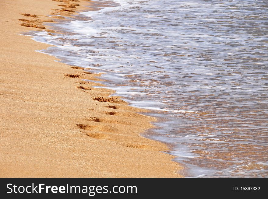 Tropical beach with footsteps and few surf