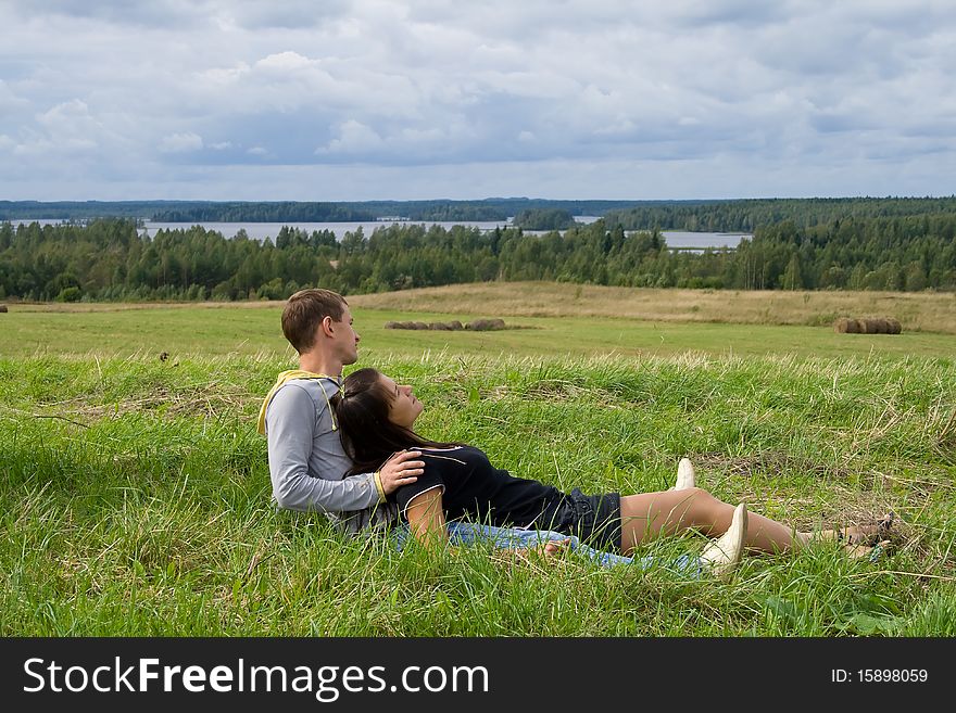 Young couple sits on a grass and looks afar. Young couple sits on a grass and looks afar