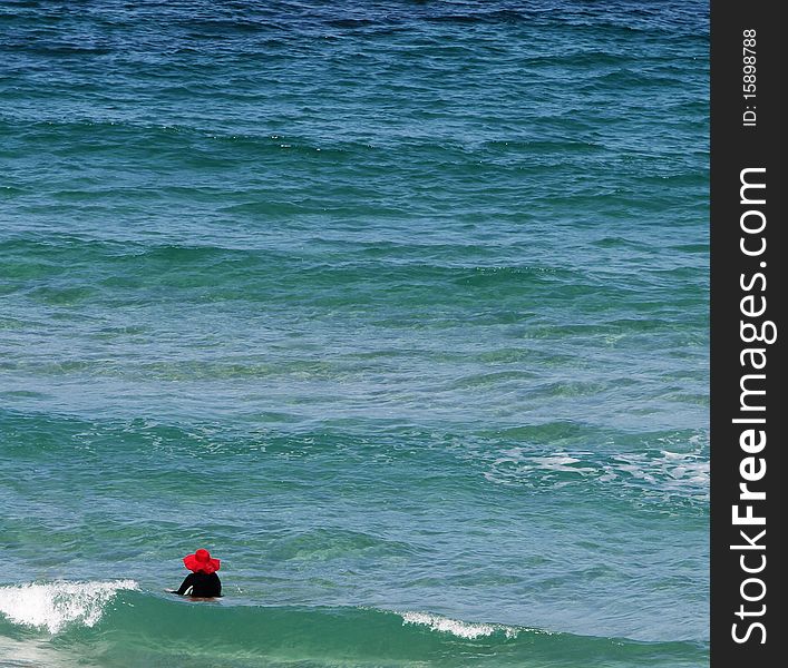 Senior lady with a big red hat enjoying dipping in the beautiful sea. Senior lady with a big red hat enjoying dipping in the beautiful sea