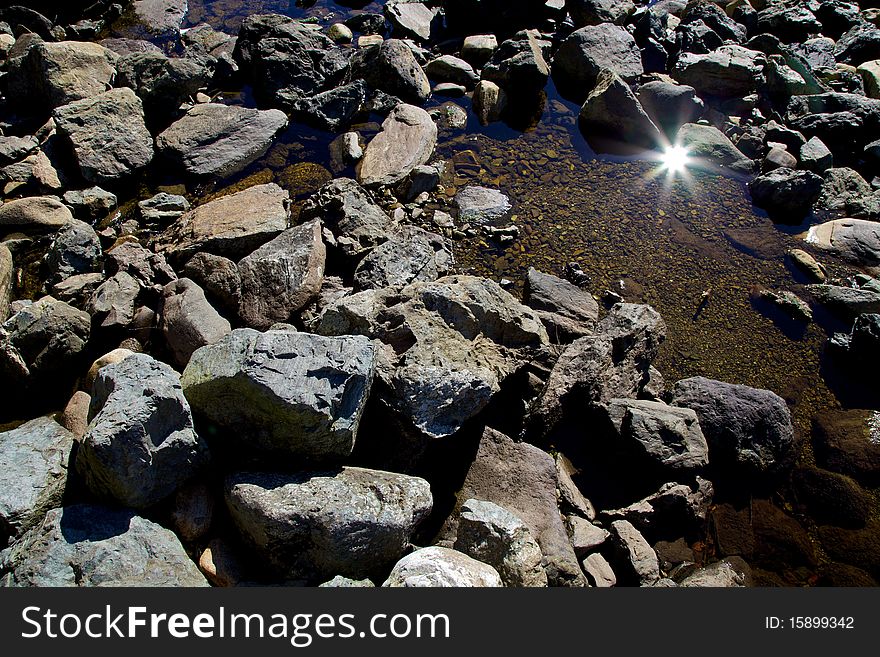 Sun reflecting off a pond with seawater on a rocky beach. Sun reflecting off a pond with seawater on a rocky beach.