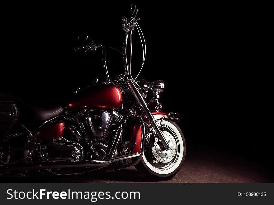 Classic motorcycle with high handlebar. maroon chopper in the dark.