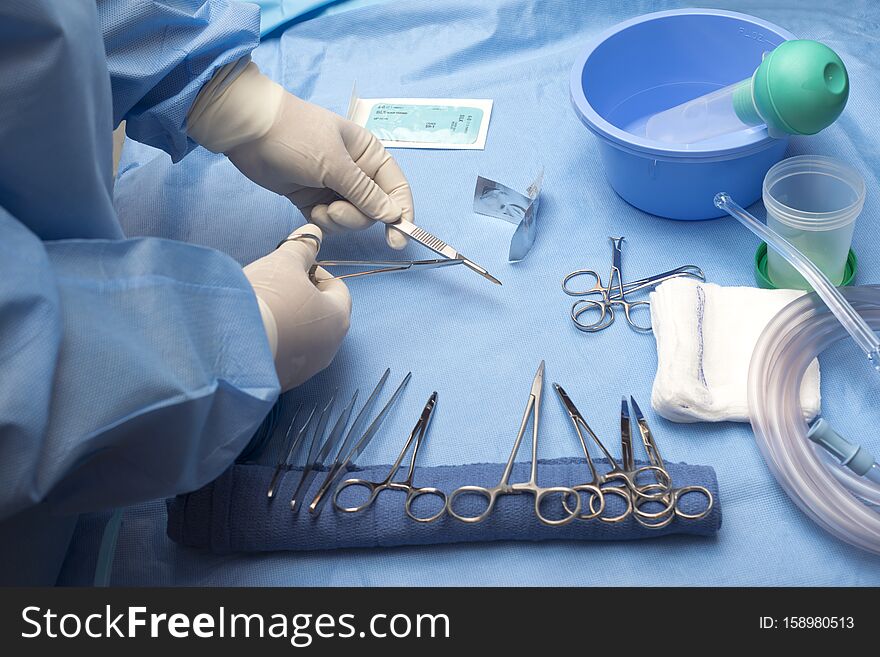 Surgical technician loads scalpel with surgical blade on sterile table. Surgical technician loads scalpel with surgical blade on sterile table