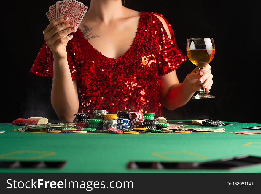 Girl in evening dress plays poker in a casino. focus on the card and focus