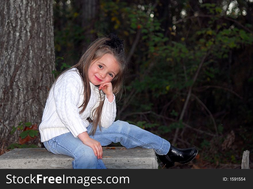 I'm adorable!  I'm just sitting here posing for this picture and I think I look sooo cute.  I'm dressed in blue jeans, a white sweater and black boots.  I have long brunette hair and brown eyes.  The setting is outdoors.