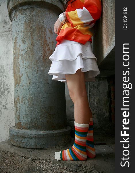 Girl wearing striped top and socks with mini skirt next to a big pipe. Girl wearing striped top and socks with mini skirt next to a big pipe