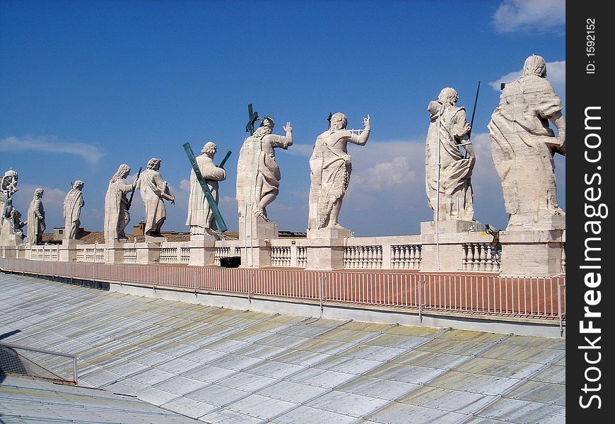 Statues of apostles looking down from the roof of St.Peter's Basilica in Vatican. Seen from behind against the blue sky. Statues of apostles looking down from the roof of St.Peter's Basilica in Vatican. Seen from behind against the blue sky.