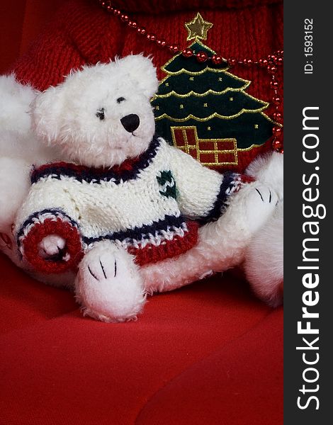 White Christmas teddy bear sitting on a red chair