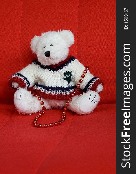 White Christmas teddy bear sitting on a red chair