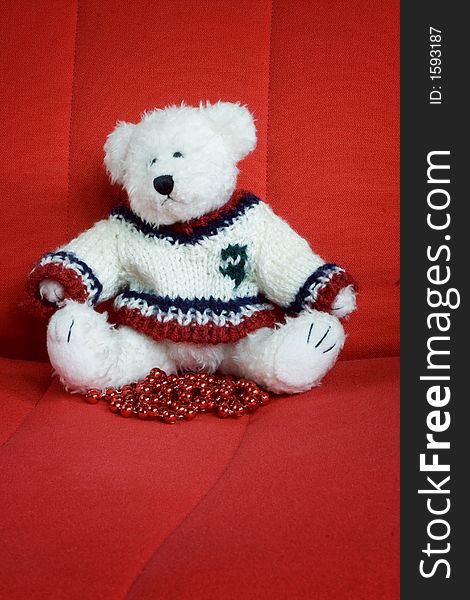 Christmas teddy bear toy sitting on a red chair