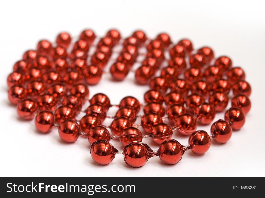 Red beads on white background in shape of a whirl