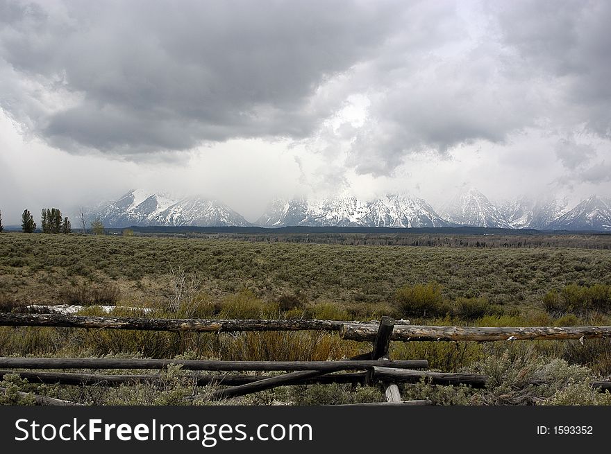 Rustic fenceline with the cloud covered Grand Tetons in the background. Rustic fenceline with the cloud covered Grand Tetons in the background.