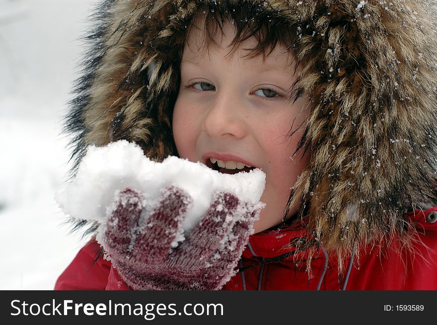 Portrait of young boy in fur hat  eating first snow. Portrait of young boy in fur hat  eating first snow.