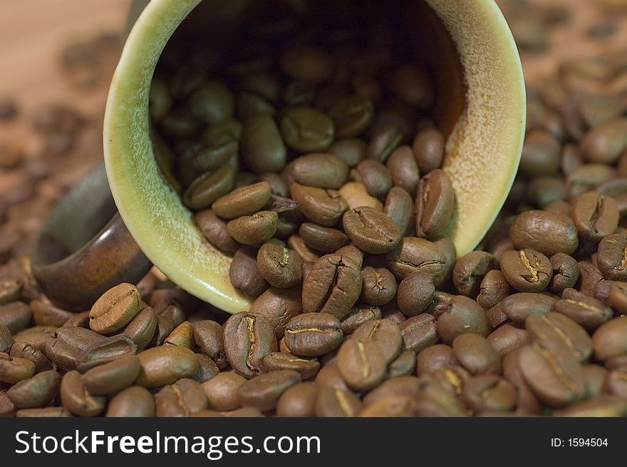 Brown cup filled with coffee beans against wooden background