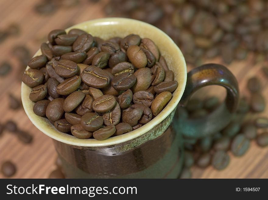 Brown cup filled with coffee beans against wooden background