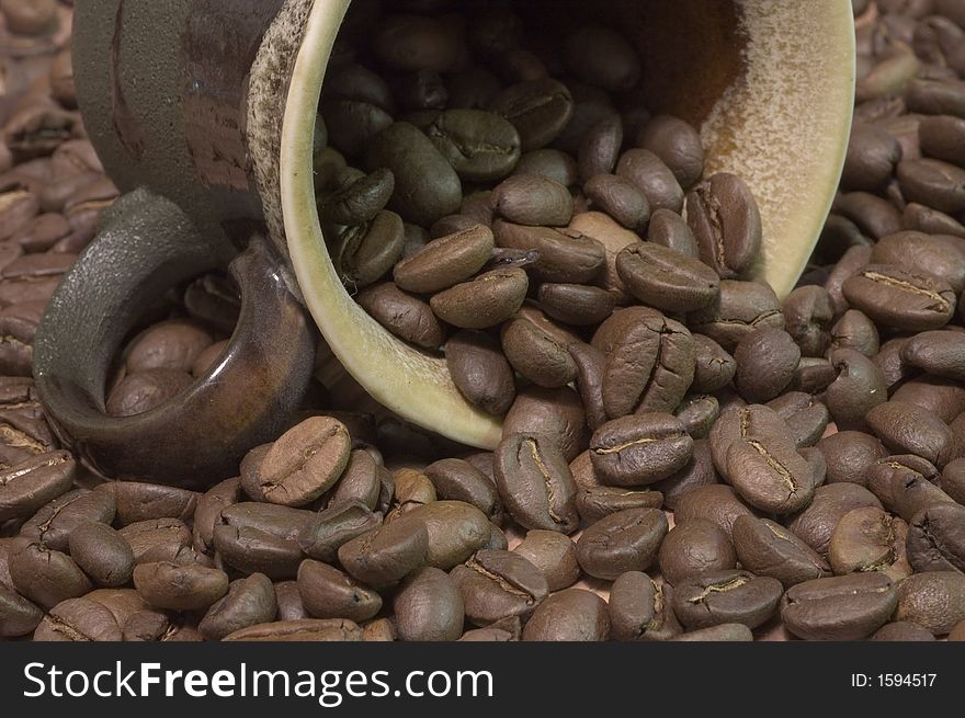 Brown cup filled with coffee beans against wooden background